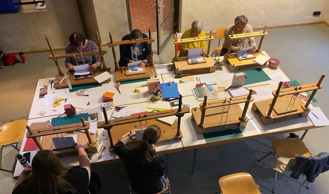 Personen sitzen am Tisch und binden Bücher
