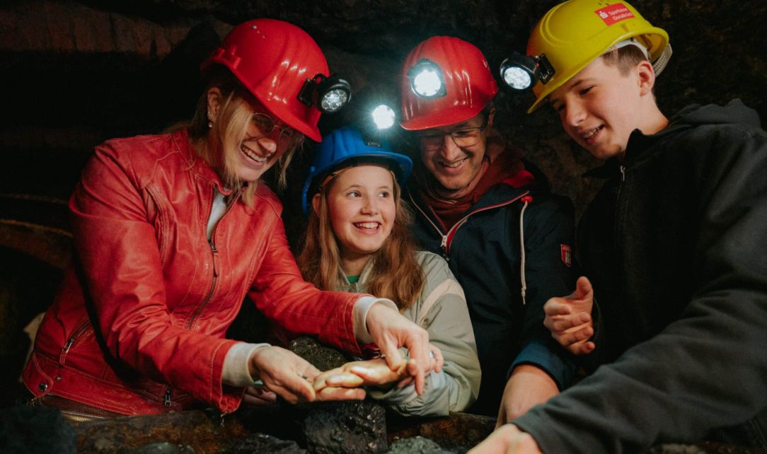 Eine Familie mit Helm und Lampe im Bergwerksstollen